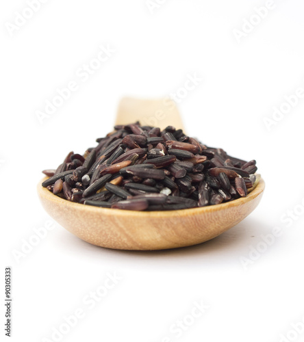 Dark violet rice on wooden spoon isolated on white background