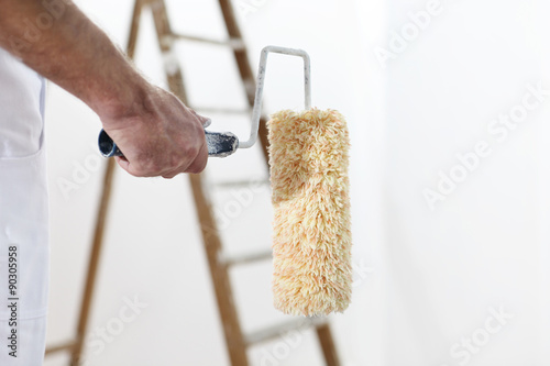 painter man at work with a paint roller and ladder,  close up photo