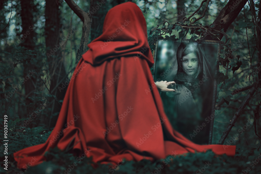 Mysterious hooded woman in front of a magical mirror Mysterious hooded woman in front of a magical mirror