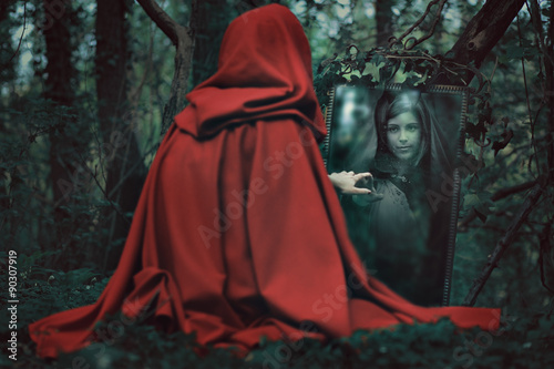Mysterious hooded woman in front of a magical mirror