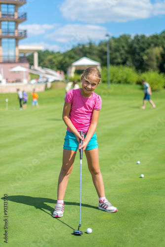 Cute little girl playing golf on a field outdoor. Summertime © lexmomot