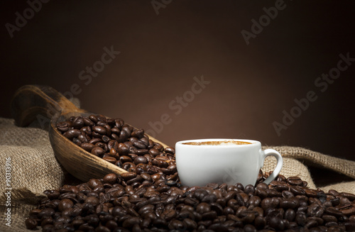 White cup with coffee beans on dark background