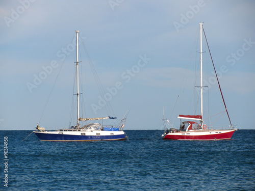 Two anchored yachts with deflated sails on the sea 