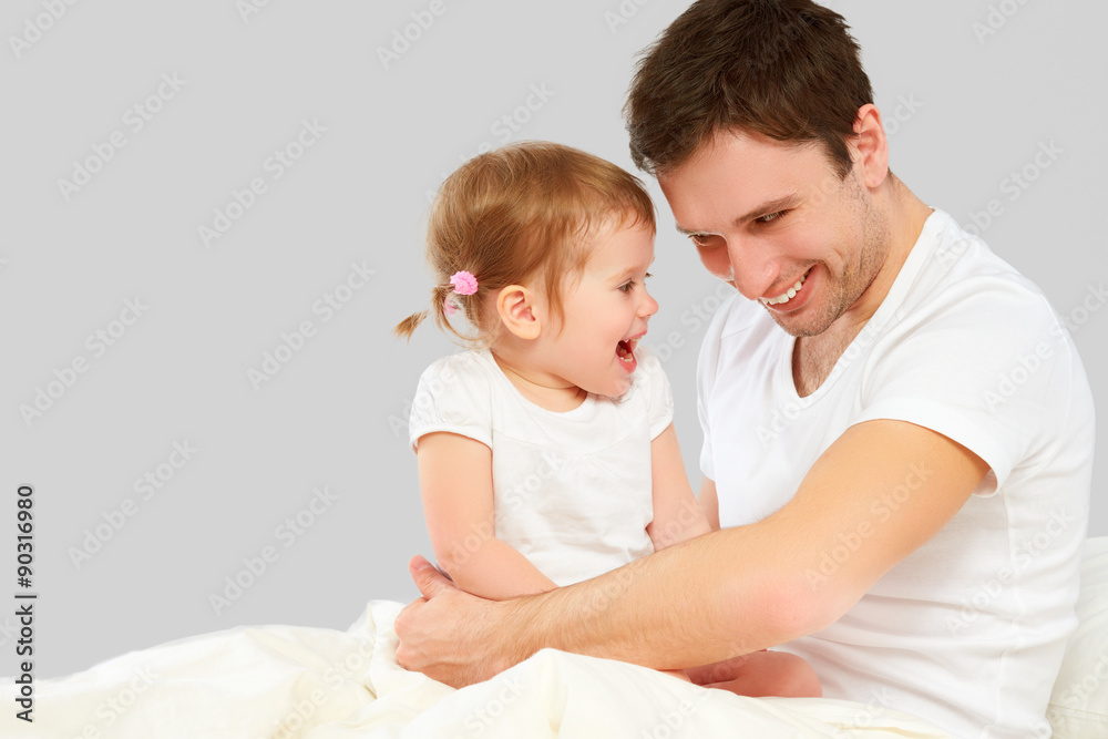 Happy family father and baby daughter playing in bed Happy family father and baby daughter playing in bed