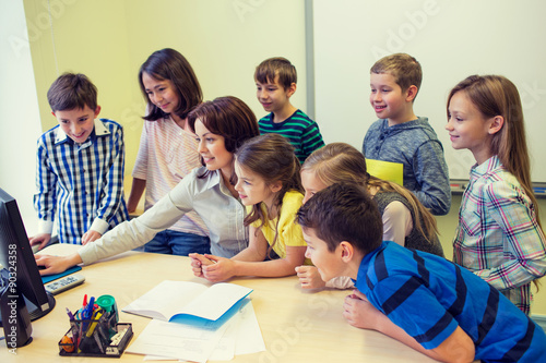 group of kids with teacher and computer at school