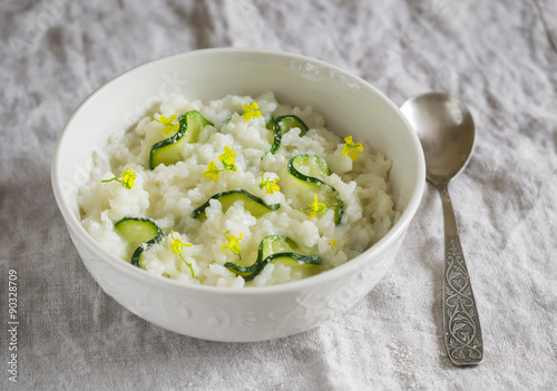 risotto with zucchini in a white bowl on a light surface