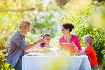 Girls first ! A grey hair father is serving melon to his daughter for a nice family lunch in the garden