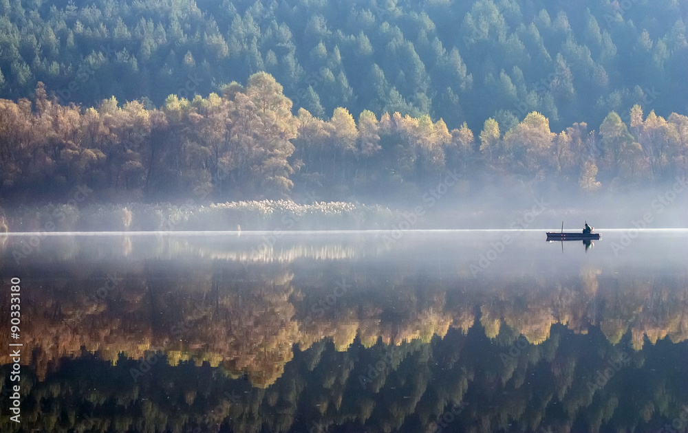 One angler fishing on a misty lake. - obrazy, fototapety, plakaty 