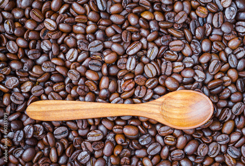 Wooden spoon on roasted coffee beans background