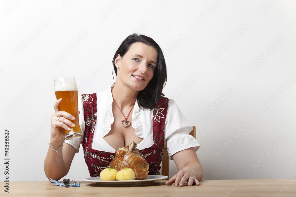 Bayerische Frau in einem Dirndl mit Schweinshaxe Bayerische Frau in einem Dirndl mit Schweinshaxe