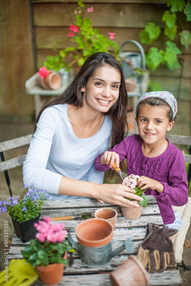mother and daughter are repotting plants at the garden table mother and daughter are repotting plants at the garden table