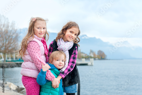 Outdoor portrait of 3 cute little girls, wearing warm coats