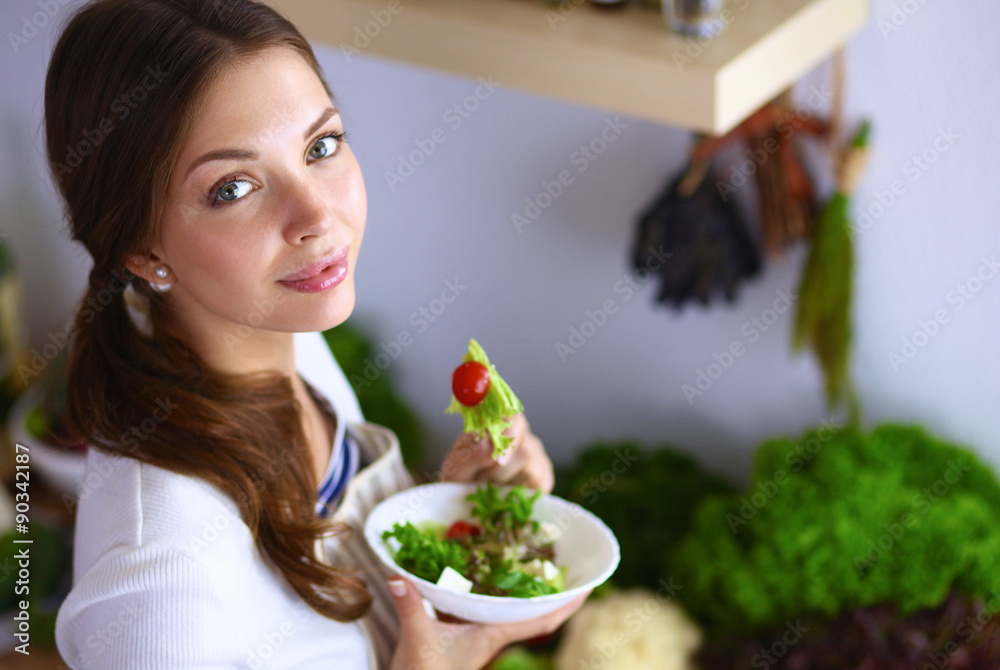 Young woman eating salad and holding a mixed salad Young woman eating salad and holding a mixed salad