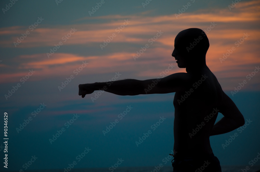 Sunset silhouette of a man practicing martial arts