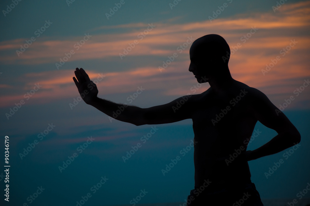 Sunset silhouette of a man practicing martial arts