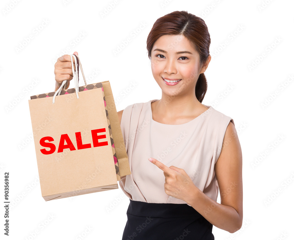 Asian woman finger point to shopping bag and showing a word sale Asian woman finger point to shopping bag and showing a word sale
