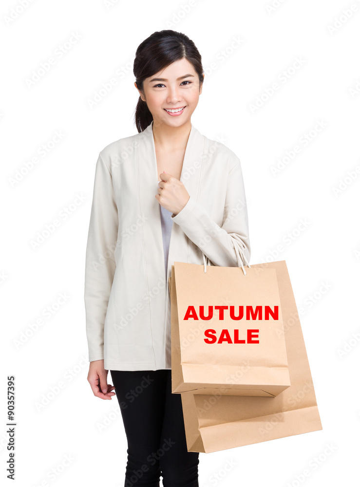 Young woman holding shopping bag and showing autumn sale Young woman holding shopping bag and showing autumn sale