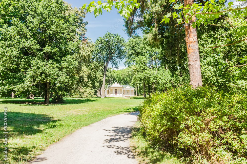 Park alley with pavilion on the background