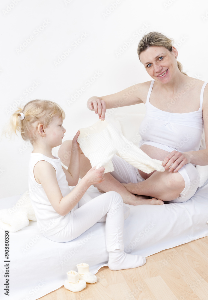 little girl and her pregnant mother with clothes for a baby
