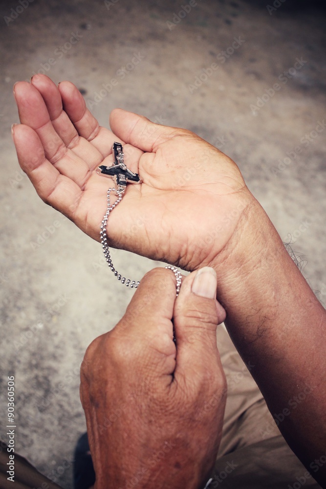 Senior man hands praying with cross