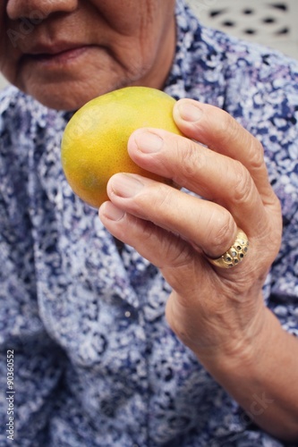  Senior woman eating orange fruit