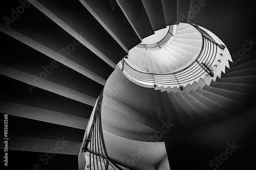 Black and white photograph of spiraling staircase shot from low angle.