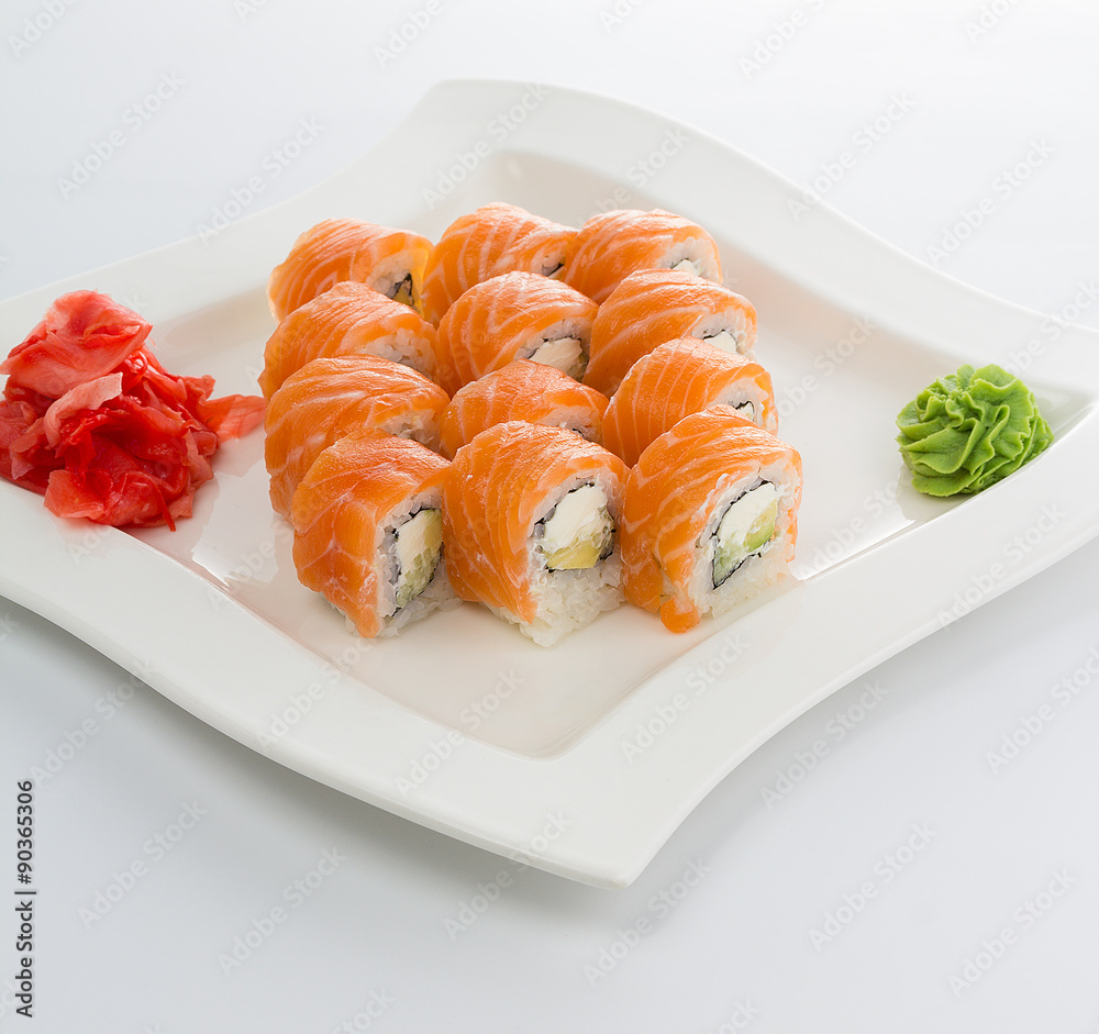 Salmon (philadelphia) sushi roll on a white plate with ginger and wasabi Salmon (philadelphia) sushi roll on a white plate with ginger and wasabi