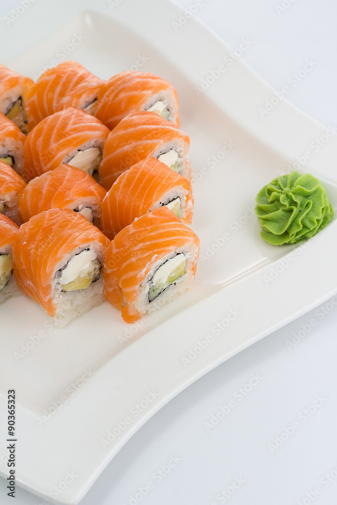 Salmon (philadelphia) sushi roll on a white plate with ginger and wasabi Salmon (philadelphia) sushi roll on a white plate with ginger and wasabi