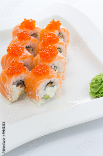 Salmon (philadelphia) sushi roll on a white plate with ginger and wasabi