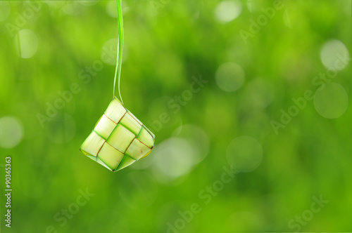 Ketupat or rice dumpling is a local delicacy during the festive season. Ketupat, a natural rice casing made from young coconut leaves for cooking rice on a bokeh or blur background. © Mohd Khairil