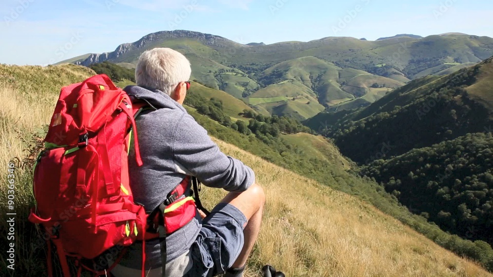 Hiker sitting on a rock admiring Basque Country scenery Hiker sitting on a rock admiring Basque Country scenery