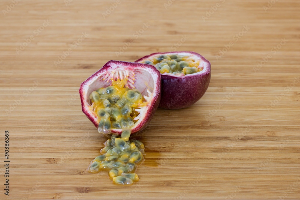 Close-up of a split passion fruit (passionfruit, purple granadilla (Passiflora edulis)), seeds on a wooden table.