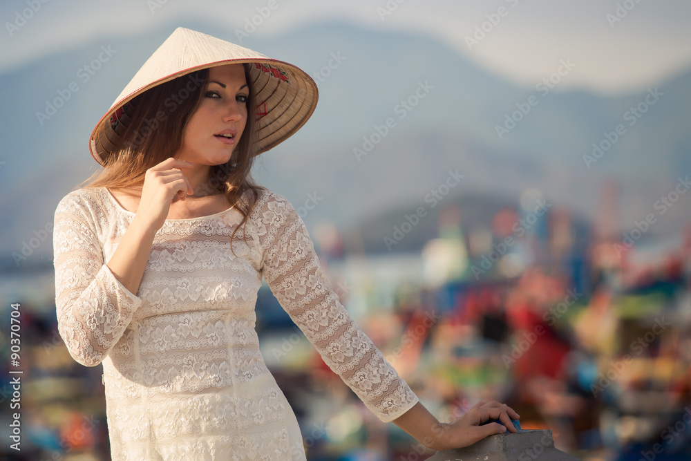 blonde girl in Vietnamese dress leans on embankment