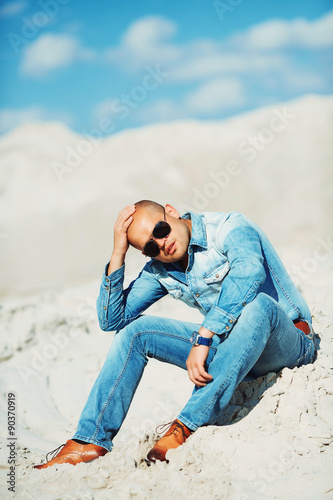 bronzed man sitting on the sand, holding his head © ostap_davydiak
