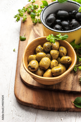Assorted olives with oregano on the white wooden table vertical