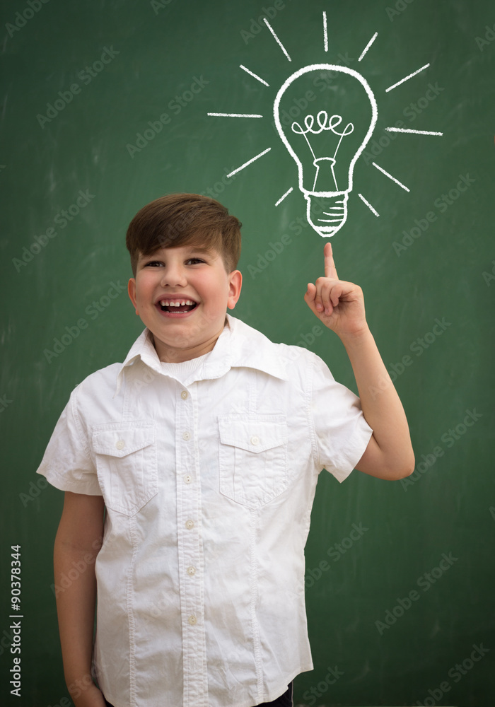 happy child against blackboard with drawing light bulb idea