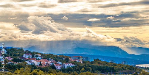 Canvas Print Small town in the valley on the background of stormy skies.