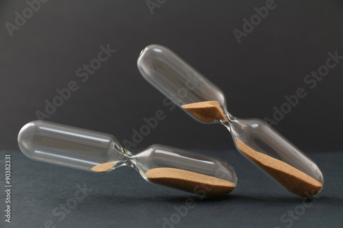 Two sand clocks in different positions and with different sand rests. Two different tilt position. Tilt increases depending deadline coming. 