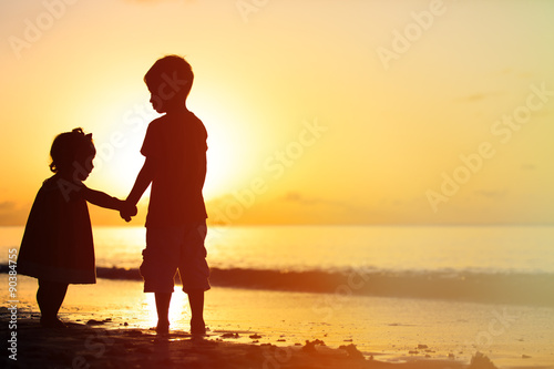 Papier peint Petit garçon et une fille, main dans la main au coucher du soleil