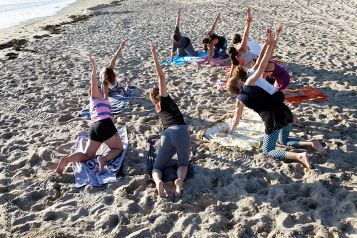 yoga teacher gives lesson to a group on the beach