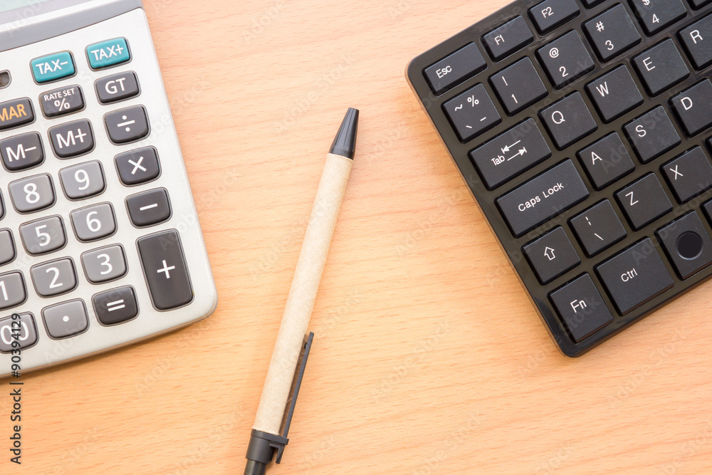 Calculator, pen and keyboard placed on a wooden table with vintage style. Calculator, pen and keyboard placed on a wooden table with vintage style.