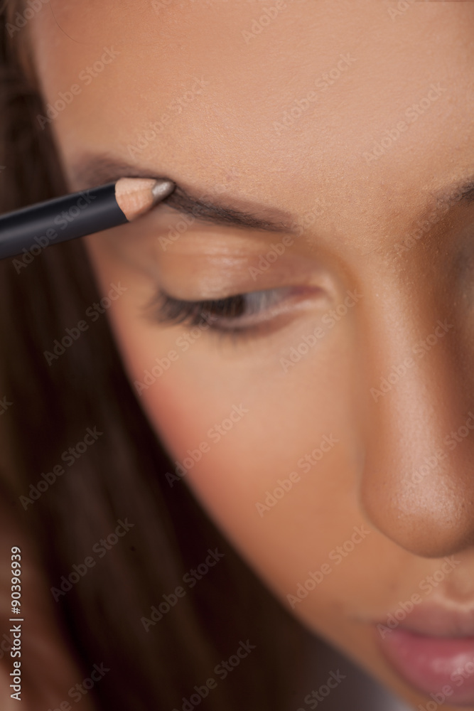 girl shaping her eyebrows with a pencil for eyebrows