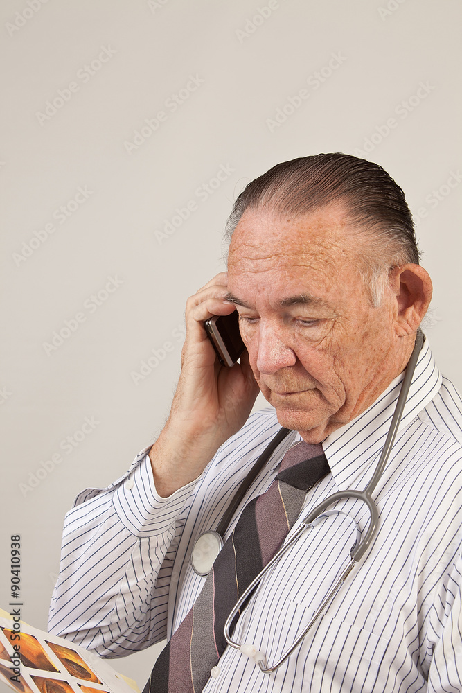 Doctor talking on phone and looking at xray. Doctor talking on phone and looking at xray.