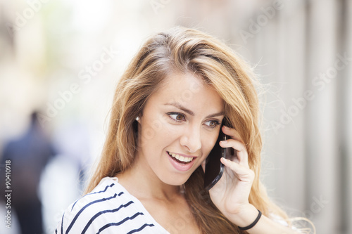 Cheerful woman talking on the phone in the street 