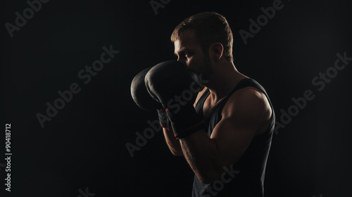 Athletic bearded boxer with gloves on a dark background © Nigrechok