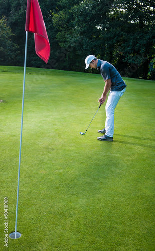 a man with a cap playing golf on a green field