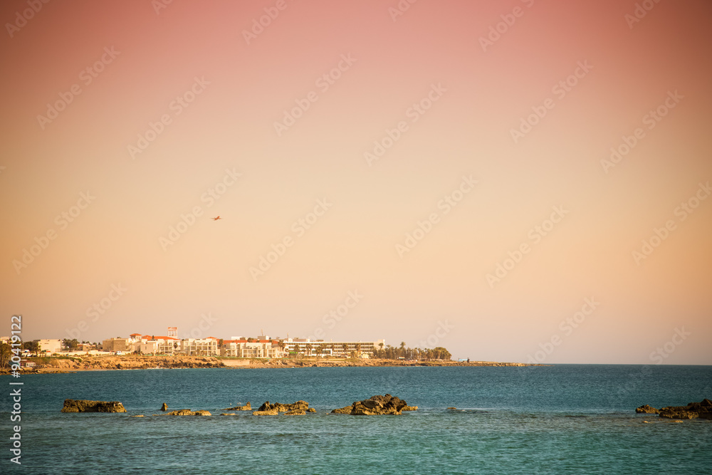 Rocky shore of the Mediterranean Sea. Town on the horizon. Toned