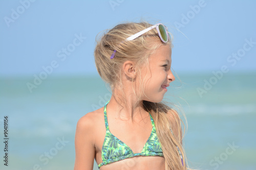 bambina bionda al mare con occhiali da sole