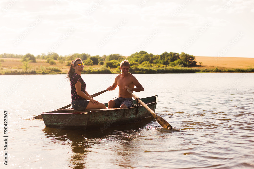 Happy romantic couple rowing a boat on lake.