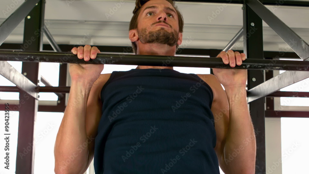 Fit man doing pull ups in fitness studio